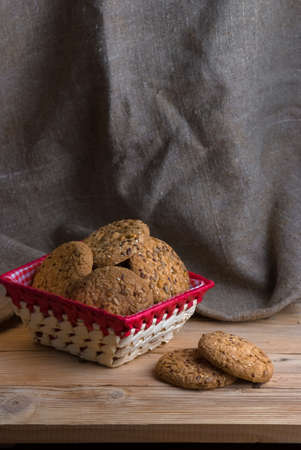 homemade oat cookies with sunflower seeds in and near basket on wooden table