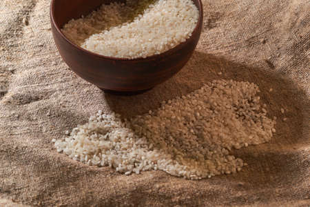 Raw rice in bowl on sackcloth. Uncooked foodの写真素材