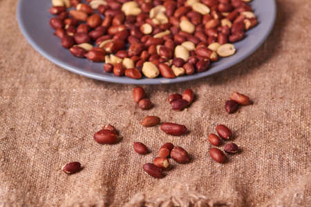 Fried Roasted peanut seed on blue plate on sackcloth background