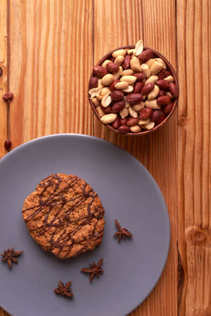 Fried Roasted peanut seed in clay bowl and chocolate cookies on plate.