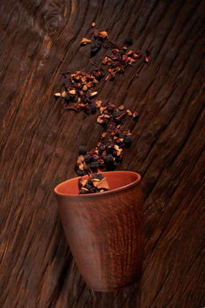 cup and dry tea leaves isolated on a wooden table