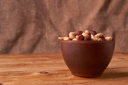 Deep fried peanuts in clay bowl over rustic wicker backgroundの写真素材