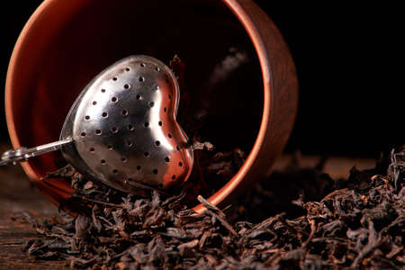 dry black chinese tea set,with strainer closeup,cups and teapot on background over wood board