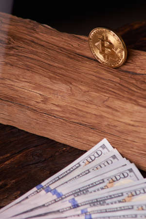 Beautifully arranged bills 100 dollar and gold coin bitcoin on a gray background. Bitcoin...