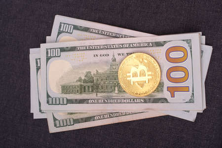 Golden bitcoin on hundred dollar bills