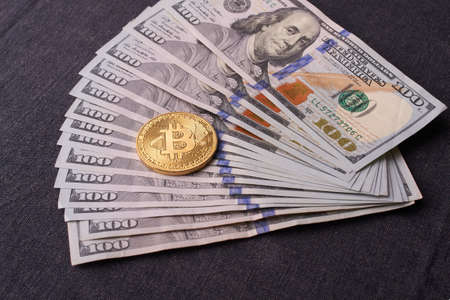 Golden metal bitcoin on dollar bills background. a lot of money in cash. 100 dollars texture. dear bitcoin. Gold coin. Profit from miningの写真素材