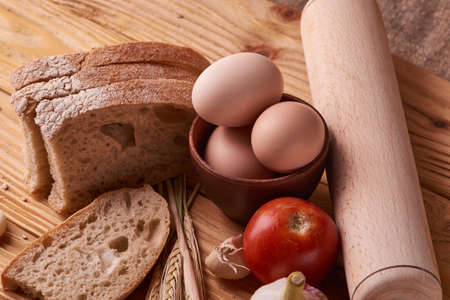 fresh delicious bread, concept for baking. Eggs in clay bowl and wheat sprouts on wooden table