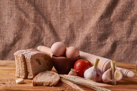 fresh delicious bread, concept for baking. Eggs in clay bowl and wheat sprouts on wooden tableの写真素材