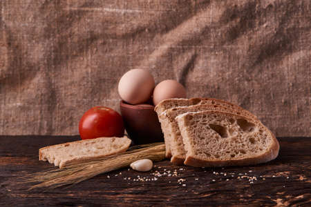fresh delicious bread, concept for baking. Eggs in clay bowl and wheat sprouts on wooden table