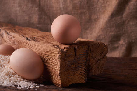 Bunch of rice and uncooced eggs on wooden table