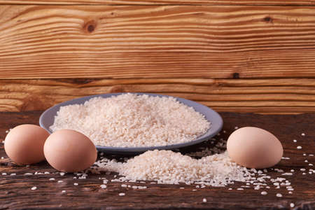 Empty gray plate with grains of rice and eggs on wooden table