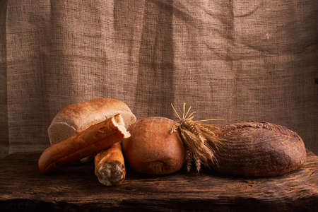 Different bread and wheat on the rustic table. Selective focus