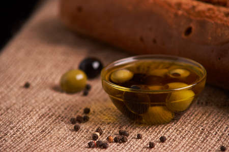 fresh bread baguette with olive oil, olives. cheese and rosemary on wooden backgroundの写真素材