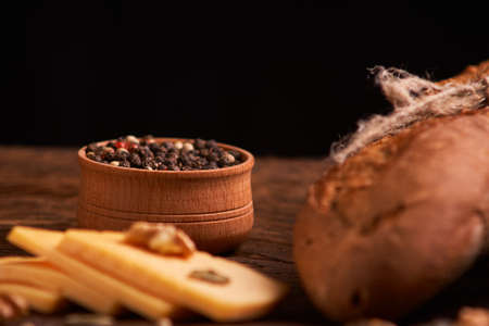 Peppercorns in a wooden bowl on table with cheese.