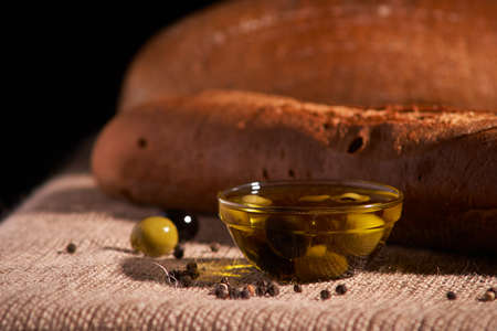 fresh bread baguette with olive oil, olives. cheese and rosemary on wooden backgroundの写真素材