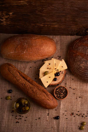Slices of cheese on wooden desk between different breadsの写真素材