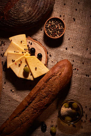 Traditional Dutch semi hard cheese served with olives on rural table with sackingの写真素材