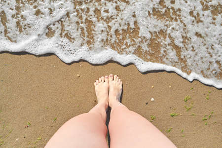 Standing on the beach with ocean wave cover the leg top viewの写真素材