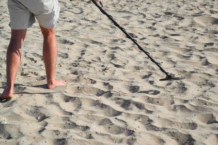 Man with a metal detector on a sea sandy beachの写真素材