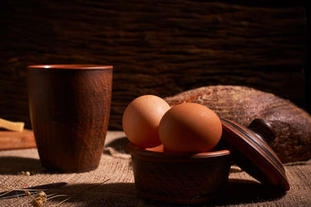eggs, bread and milk glass on wooden table and dark wooden background