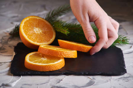 Fresh slised oranges on the gray background and with spruce branch