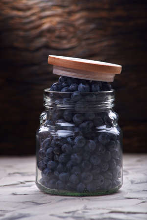 fresh and tasty blueberry berries in a glass jar and with a checkered napkinの写真素材