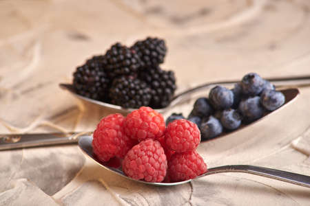 mix of fresh delicious berries lying on spoons