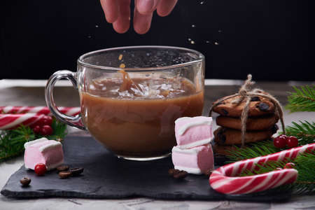 Coffee with milk preparation in glass cup with marshmallow on black background