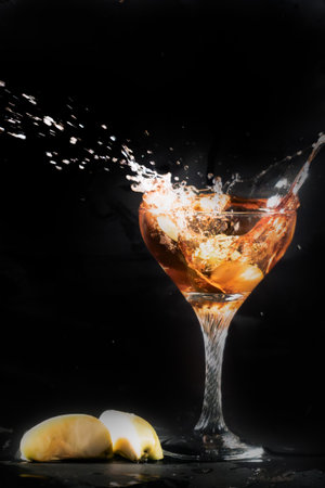 Splash in a martini glass on a black background with appleの写真素材