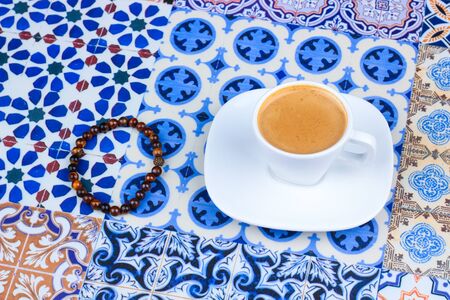 Cup of Arabian Coffee on an Oriental Colorful Background / Cup of Espresso on an Oriental Colorful Background with Flowers, Rings, and Tamr datesの写真素材