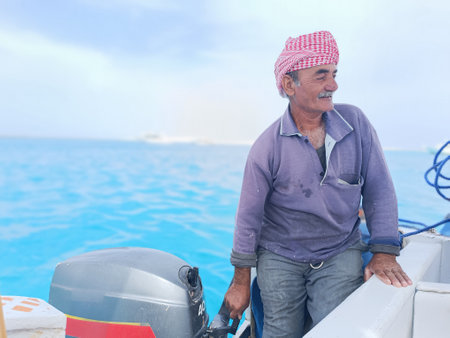 Old Sailor in the Sea Riding and Sailing with his Boat An old sailor with a white with a white mustache who is wearing a Bedouin Scarf on his headの写真素材