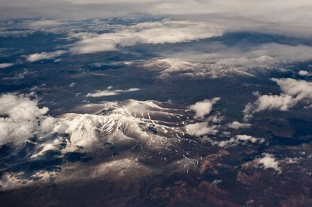 Aerial photography of snowy mountains covered with cloudsの写真素材