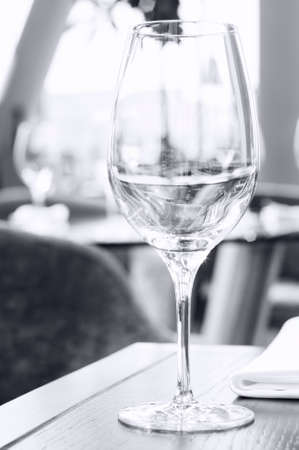 An empty single wine glass on a wooden table in a restaurant.の写真素材