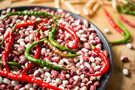 Lots of chili peppers and beans on the wooden surface. Selective focus.の写真素材