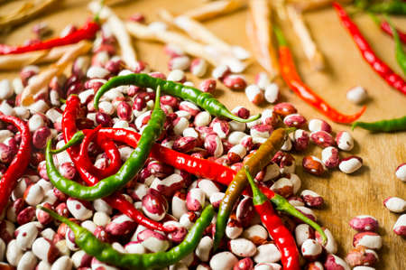 Lots of chili peppers and beans on the wooden surface. Selective focus.の写真素材