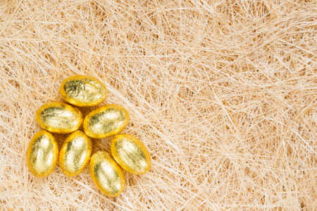 A background with golden eggs on straw.の写真素材