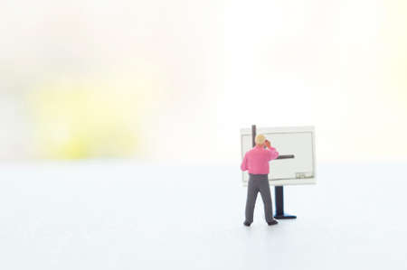 A conceptual photo with a toy or other professional at the empty drawing board with a place for your text. Focus on a figurine of a human.の写真素材