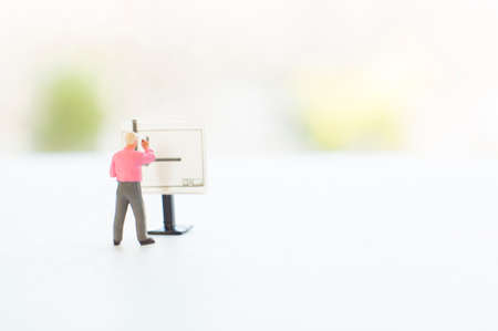 A conceptual photo with a toy or other professional at the empty drawing board with a place for your text. Focus on a figurine of a human.の写真素材