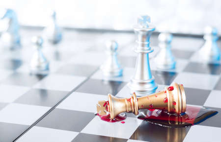 A conceptual photo with chess pieces and blood on a chessboard. Business, law or political concept, which could represent the war of corporations, geopolitical situation and so on. Selective focus.の写真素材