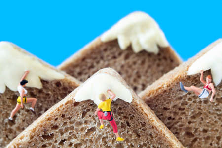 A group of toy mountaineers on mountains, made of healthy rye bread and creamy cheese. Ecotourism and healthy eating concept.の写真素材