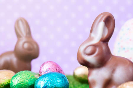 Easter bunnies, made of white and milk chocolate against a polka dot background.の写真素材
