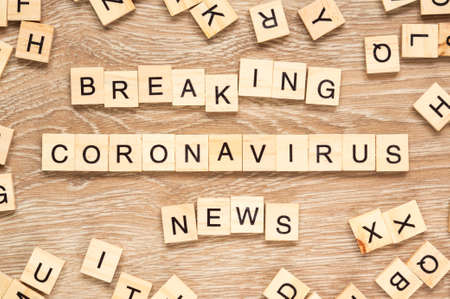 The words `Breaking Coronavirus News` spelt out with letter tiles on the wooden backgroundの写真素材