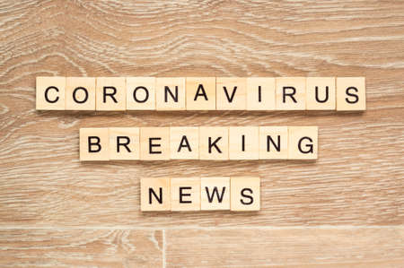 The words "Coronavirus Breaking News" spelt out with letter tiles on the wooden backgroundの写真素材