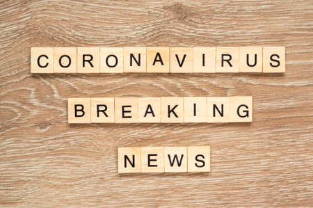 The words "Coronavirus Breaking News" spelt out with letter tiles on the wooden backgroundの写真素材