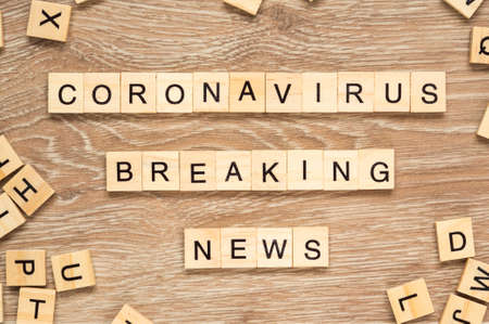 The words "Coronavirus Breaking News" spelt out with letter tiles on the wooden backgroundの写真素材