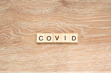 The word "Covid" spelt out with letter tiles on the wooden backgroundの写真素材