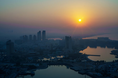 Aerial view of Abu Dhabi in the morning light, as the rising sun casts a golden glow over the city's modern skyline.の写真素材