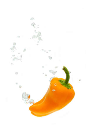 Capsicum falling into water, with air bubbles, in front of white background, union of the three things essential to live which is air, water and nutritionの写真素材