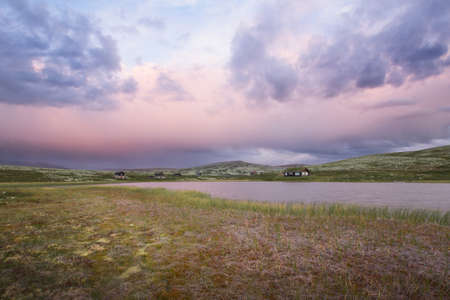 Huts on lake in landscape of Norway during sunsetの写真素材