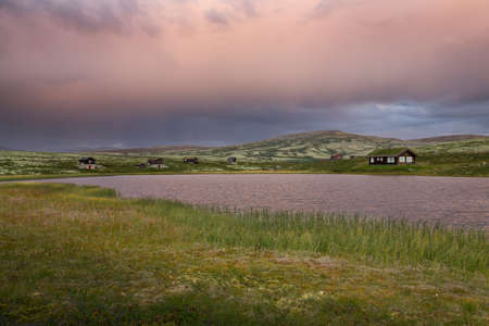 Huts on lake in landscape of Norway during sunsetの写真素材